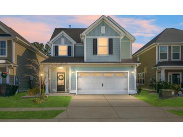 Charming two-story house with a light blue exterior, white garage door, and manicured lawn at 563 Alderly Dr, Moncks Corner, SC 29461