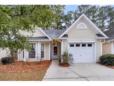 Charming yellow house with a white garage door and landscaping at 4845 Carnoustie Ct, Summerville, SC 29485