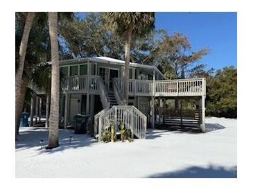 Elevated two-story home with wrap-around decks, stairs, and fenced yard at 613 Pompano St, Edisto Island, SC 29438