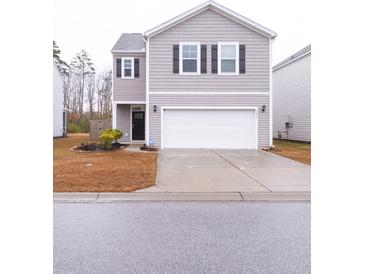 Two-story house with gray siding, white garage door, and landscaping at 9806 Sickle Dr, Ladson, SC 29456