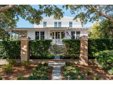 White two-story home with a metal roof, brick pillars, and lush landscaping at 222 Haddrell St, Mount Pleasant, SC 29464