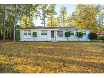White brick ranch house with landscaped yard and mature trees at 411 Constance St, Walterboro, SC 29488