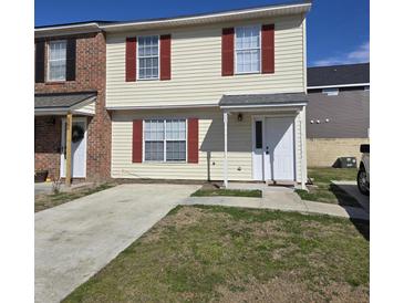 Brick and vinyl siding townhouse with red shutters and a concrete driveway at 6884 Shahid Row, North Charleston, SC 29418