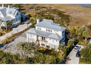 Aerial view of a white two-story house with a metal roof, situated near water at 2618 Raven Dr, Sullivans Island, SC 29482