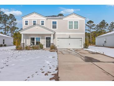 Two-story house with a white garage door and porch swing, freshly covered in snow at 261 Firewheel Ct, Summerville, SC 29486