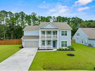 Two-story light blue house with gray roof, two-car garage, and landscaped yard at 4041 Oxeye Loop, Johns Island, SC 29455