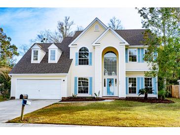 Two-story yellow house with blue shutters, a white garage, and a well-maintained lawn at 212 Thomaston Ave, Summerville, SC 29485