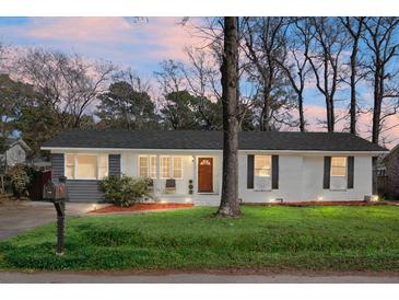 Charming ranch home with gray and white exterior, well-manicured lawn, and mature trees at 1385 Fairfield Ave, Charleston, SC 29407