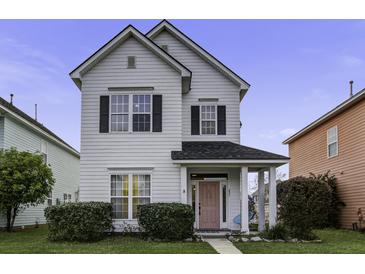 Charming two-story home with a well-maintained lawn and inviting front porch and beautiful pink front door at 221 Trillium Ave, Summerville, SC 29483