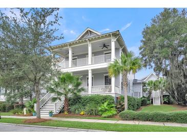 Charming two-story home featuring double porches, a landscaped yard with palm trees, and a classic coastal design at 164 River Green Pl, Charleston, SC 29492