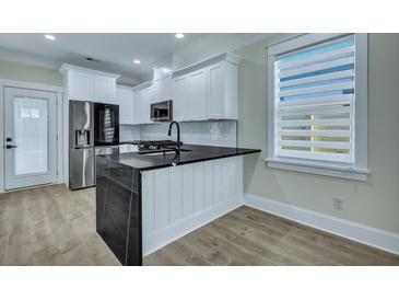 Bright kitchen featuring white cabinets, stainless steel appliances, and a black countertop island at 2035 Beech Ave, North Charleston, SC 29405