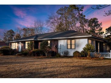 Charming single-story home featuring a mix of brick and siding with a well-manicured lawn and lush landscaping at 209 E 4Th S St, Summerville, SC 29483