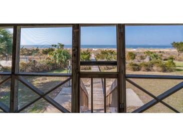 Scenic view from a screened porch overlooking a sandy path to the beach and ocean at 3408 Palmetto Blvd, Edisto Island, SC 29438