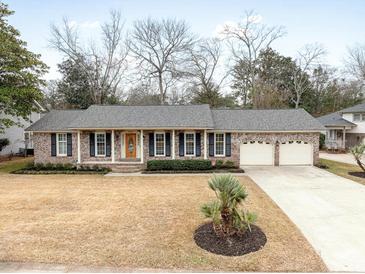 Charming brick home with a two-car garage, complemented by a well-manicured lawn and a tasteful front yard landscaping at 1043 Dominion Dr, Hanahan, SC 29410