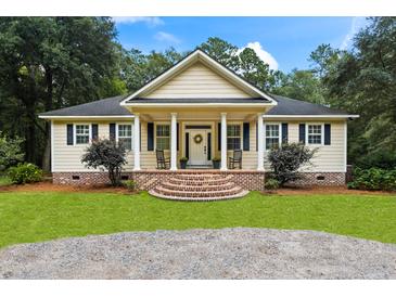 Charming single-story home featuring a cozy front porch with rocking chairs and well-manicured landscaping at 140 Old Plantation Ln, Moncks Corner, SC 29461
