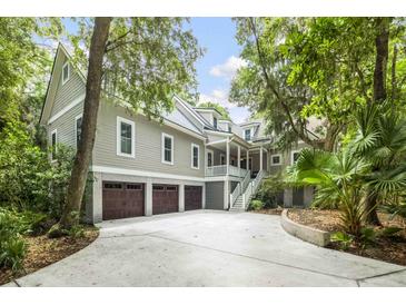 Stunning exterior showcasing the home's architectural design, three-car garage, and lush, mature landscaping at 2932 Old Drake Dr, Seabrook Island, SC 29455