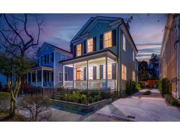 Charming two-story home with a welcoming front porch, landscaped garden, and a secure black iron fence at 3 Bee St, Charleston, SC 29403