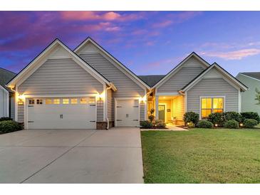 Charming one-story home featuring a manicured lawn, a two-car garage and a welcoming front porch at 205 Potters Pass Dr, Summerville, SC 29486