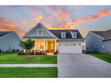 Charming home with a manicured lawn, inviting front porch, and a two-car garage at sunset at 306 Autumn Azalea Way, Summerville, SC 29486