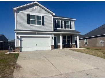 Two-story home with gray siding, a two-car garage, and a well-maintained lawn and long concrete driveway at 619 Ravens Wood Rd, Summerville, SC 29486