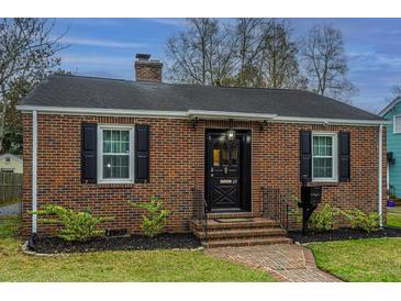 Charming brick home with black shutters, manicured landscaping, and a brick pathway to the front door at 69 Folly Road Blvd, Charleston, SC 29407