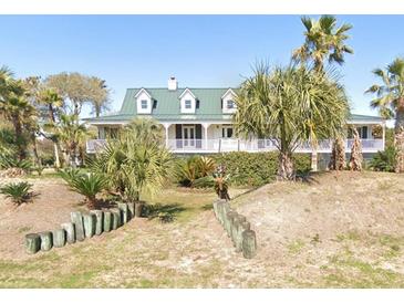 Charming coastal home featuring a green metal roof, white siding, and a welcoming front porch surrounded by palm trees at 214 Charleston Blvd, Isle of Palms, SC 29451
