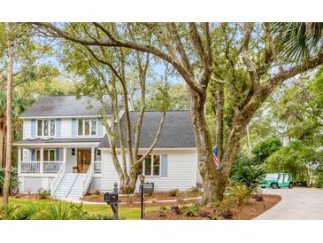 Charming two-story home with a light gray exterior, blue shutters, and mature trees at 23 Edgewater Aly, Isle of Palms, SC 29451