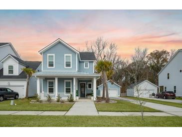 Charming two-story home with a welcoming front porch, manicured lawn, and detached garage at 2710 Mcfadden Way, Johns Island, SC 29455