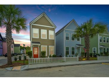 Charming colorful two-story home featuring a red door, white picket fence, and lush palm trees at 2970 Evening Tide Dr, Hanahan, SC 29410