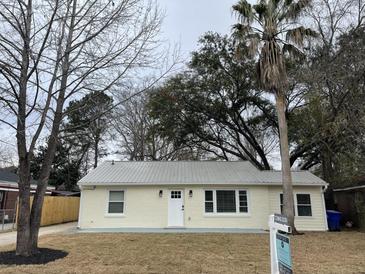 Charming single-story home featuring a metal roof, complemented by mature trees and an inviting front lawn at 1508 Greenbay Dr, North Charleston, SC 29406