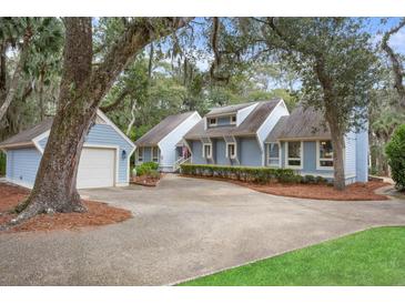 Charming blue home featuring mature trees, an attached garage, and a long driveway for ample parking at 2653 Seabrook Island Rd, Seabrook Island, SC 29455