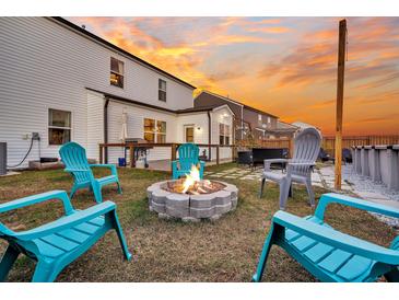 Inviting backyard with a stone fire pit and Adirondack chairs, perfect for outdoor entertaining on a cool evening at 315 Silent Bluff Dr, Summerville, SC 29486