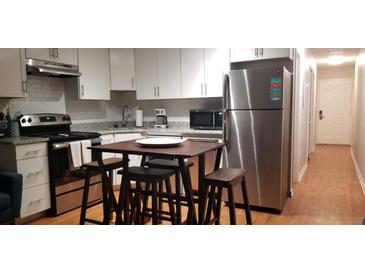 Open kitchen with stainless steel appliances, white cabinets, and a modern kitchen island with stools at 40 Bee St # 112, Charleston, SC 29403