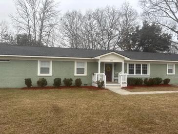 Charming single-story home with a tidy front yard, green painted brick, and a welcoming entrance at 705 Melrose Dr, Charleston, SC 29414