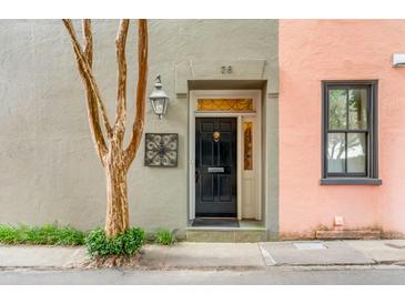 Charming home exterior featuring a black front door, vintage-style lantern, and manicured landscaping at 38 Elliott St, Charleston, SC 29401