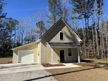 Charming beige two-story home with a single car garage, black roof, and a well-maintained front yard at 123 White Picket Ln, Summerville, SC 29483
