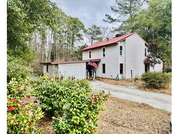 Charming two-story home with a red roof, mature trees and a beautiful garden at 204 Chamblee Rd, Walterboro, SC 29488