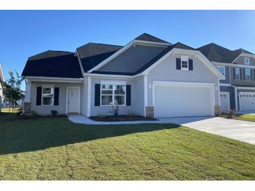 Well-manicured lawn highlights this beautiful single Gathering home with a two-car garage, a cozy white door, and black window shutters at 478 Rowley Ln, Summerville, SC 29486