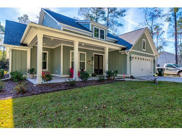 Charming home featuring a welcoming front porch and attached two-car garage at 418 Myers Mayo Rd, Ridgeville, SC 29472