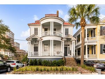 Beautiful two-story home with double balconies, white columns, red roof and landscaped yard with a palm tree at 47 Ashley Ave, Charleston, SC 29401