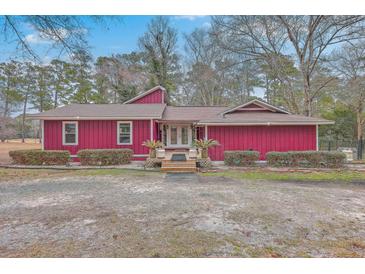 Charming red home featuring well-maintained landscaping and a welcoming entrance with double doors and mature trees at 7 Dogwood Ln, Walterboro, SC 29488