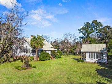 Charming home with large front yard, lush landscaping, and a guest house with a matching green metal roof at 901 Morton Waring Ln, Pinopolis, SC 29469