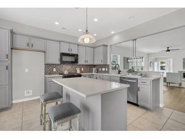 Bright kitchen features gray cabinets, stainless steel appliances, mosaic backsplash and a center island with seating at 174 Sea Lavender Ln, Summerville, SC 29486