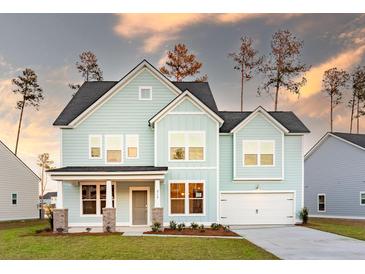 Charming two-story home with light blue siding, a well-manicured lawn, and an attached two-car garage at 1832 Nola Run, Summerville, SC 29485