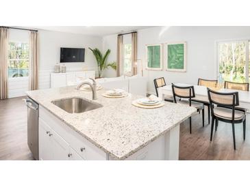 Bright kitchen features a large island with granite countertop and stainless steel sink, next to a dining area at 303 Pine Crest View Dr, Summerville, SC 29486