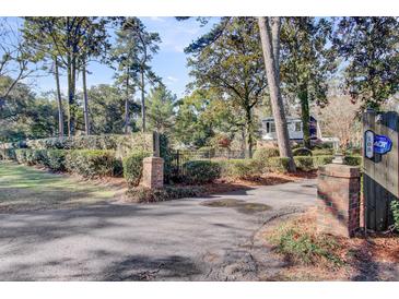 View of circular driveway with brick pillars leading to a lush property surrounded by trees and manicured hedges at 108 Tea Farm Rd, Summerville, SC 29483