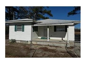 Cozy single-story home featuring white siding, a covered front porch, and a metal roof, surrounded by a chainlink fence at 1202 Forty-One Rd, Saint Stephen, SC 29479