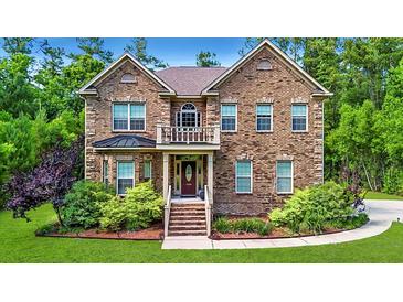 Charming brick two-story home featuring a manicured lawn and lush landscaping at 1208 Red Buckeye Ct, Moncks Corner, SC 29461
