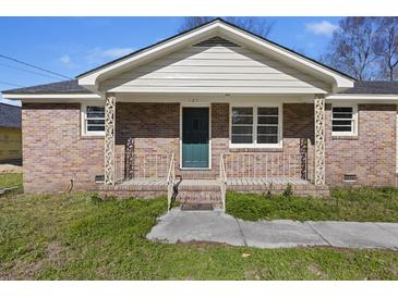 Charming brick home featuring a quaint front porch, complemented by manicured landscaping and a welcoming green door at 127 Ridge Rd, Summerville, SC 29485