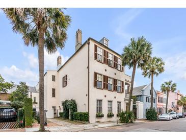 Stately stucco home boasts traditional design, brown shutters, and meticulously landscaped yard with mature palm trees at 40 State St # 1, Charleston, SC 29401